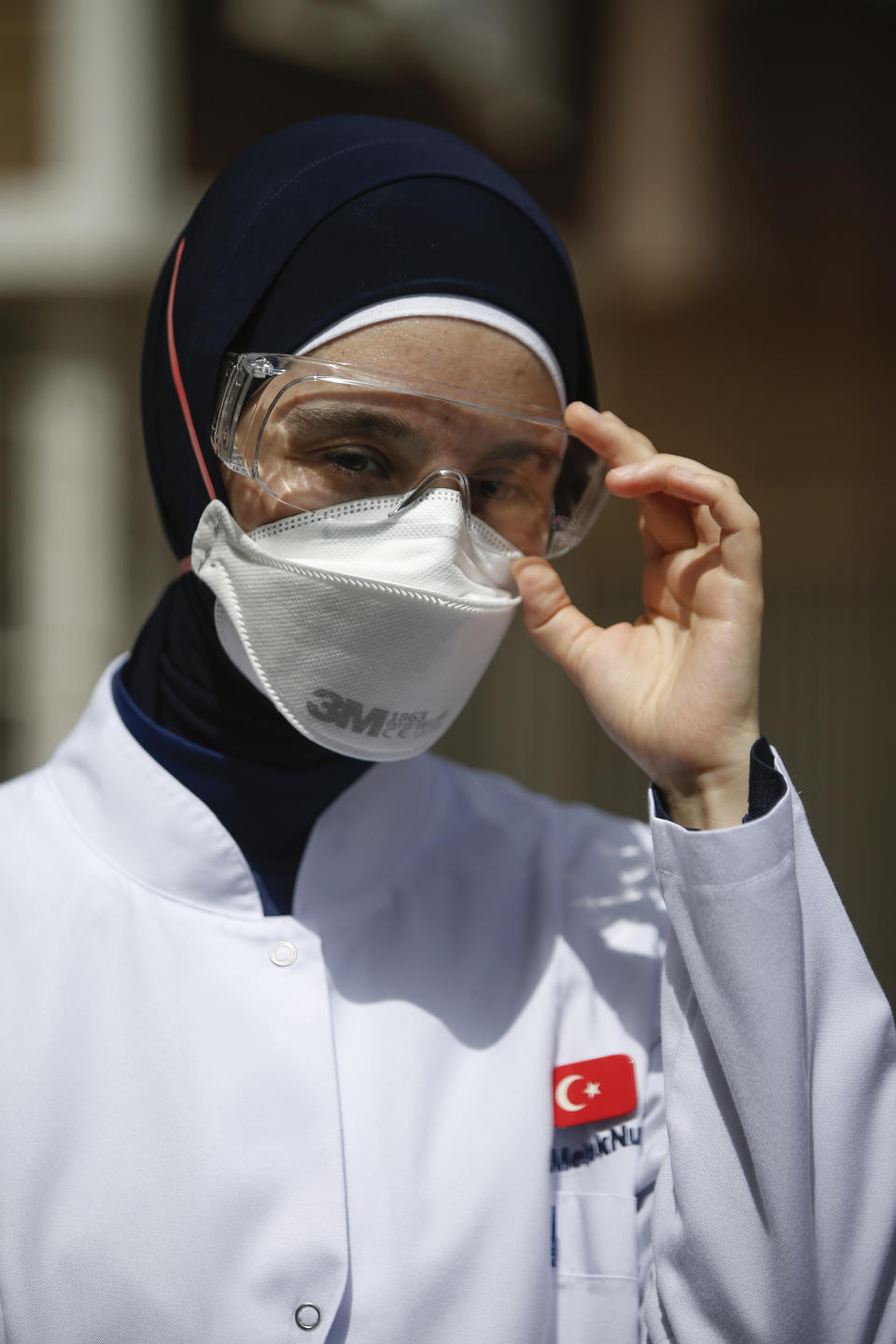 In this Friday, May 15, 2020 photo, Dr. Melek Nur Aslan, the local health director for Fatih, a large district in the historic peninsula of Istanbul adjusts her goggles as she prepares to deploy a team of contact tracers with Turkey's Health Ministry's coronavirus contact tracing team. Teams of contact tracers in Istanbul, the epicenter of the pandemic in Turkey and its most populous city, and also nationwide, are going house to house to test people experiencing COVID-19 symptoms and inform patients on isolation. (AP Photo/Emrah Gurel)