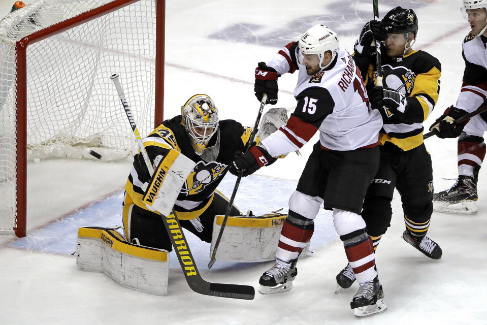Pittsburgh Penguins goaltender Tristan Jarry (35) blocks a shot deflected by Arizona Coyotes' Brad Richardson (15) with Penguins' Chad Ruhwedel defending during the first period of an NHL hockey game in Pittsburgh, Friday, Dec. 6, 2019. (AP Photo/Gene J. Puskar)
