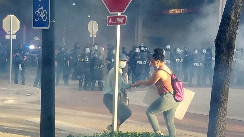 LaToya Ratlieff es ayudada a salir de una calle llena de gases lacrimógenos disparados por la policía, al final de una marcha en Fort Lauderdale para protestar por la muerte de George Floyd.