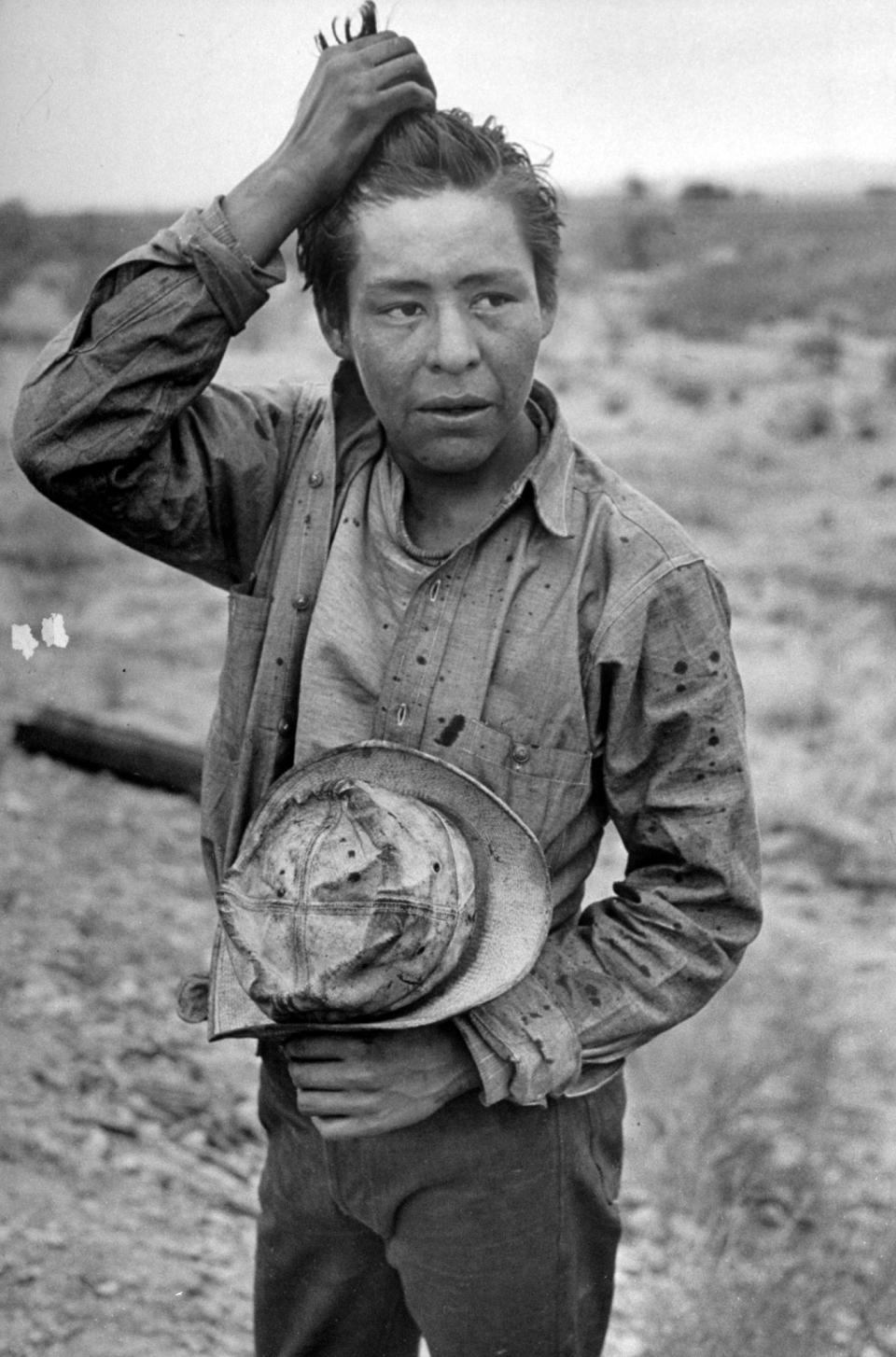 A Navajo boy running his fingers through his hair.