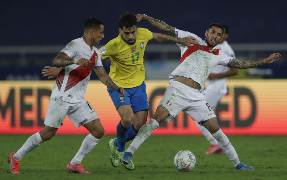 Brazil's Lucas Paqueta, center, fights for a bad with Peru's Yoshimar Yotun, left, and Sergio Pena during a Copa America semifinal soccer match at Nilton Santos stadium in Rio de Janeiro, Brazil, Monday, July 5, 2021. (AP Photo/Silvia Izquierdo)