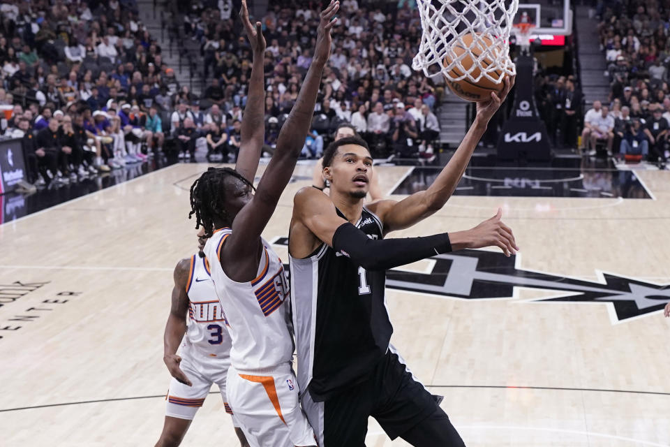 San Antonio Spurs center Victor Wembanyama (1) drives to the basket past Phoenix Suns center Bol Bol, front left, during the first half of an NBA basketball game in San Antonio, Saturday, March 23, 2024. (AP Photo/Eric Gay)