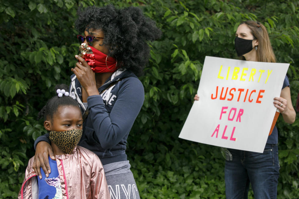 FILE - In this June 2, 2020, file photo, Ericka Ward-Audena, of Washington, stands with her daughter Elle Ward-Audena, 7, during a protest of President Donald Trump's visit to the Saint John Paul II National Shrine, in Washington. "I wanted my daughter to see the protests, it's really important. I've gotten a million questions from her because of it," says Ward-Audena, "I think the most egregious statement was 'when they start looting, we start shooting.' That crossed a line for me." Protests continue over the death of George Floyd, who died after being restrained by Minneapolis police officers. (AP Photo/Jacquelyn Martin, File)