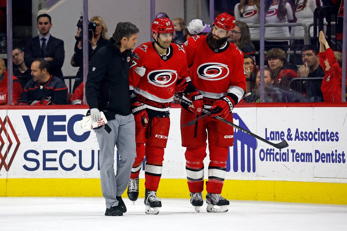 Carolina Hurricanes head athletic trainer Doug Bennett, left, and Brent Burns, right, assist Max Pacioretty off the ice following an injury during the third period of the team’s NHL hockey game against the Minnesota Wild in Raleigh, N.C., Thursday, Jan. 19, 2023.