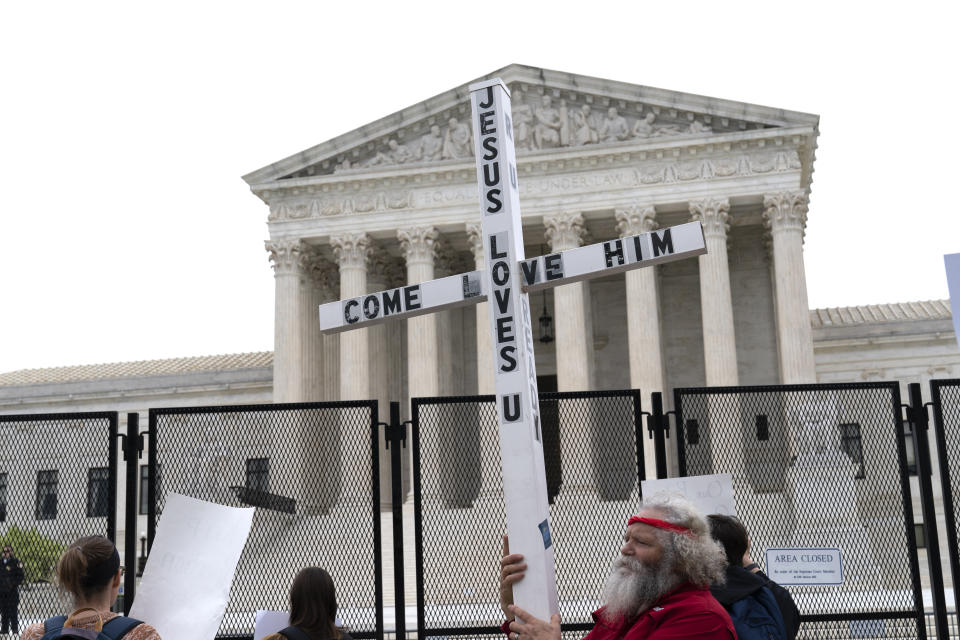 FILE - A demonstrator holding a cross protests outside of the U.S. Supreme Court, Thursday, May 5, 2022, in Washington. America’s faithful are bracing, some with cautionary joy and others with looming dread, for the Supreme Court to potentially overturn the landmark 1973 Roe v. Wade decision and end the nationwide right to legal abortion. (AP Photo/Jose Luis Magana, File)