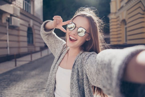 Image of young woman smiling and taking a selfie.