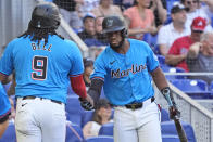Miami Marlins' Bryan De La Cruz, right, congratulates Josh Bell (9) after Bell scored on a double by Jazz Chisholm Jr., during the fourth inning of a baseball game against the Atlanta Braves, Sunday, April 14, 2024, in Miami. (AP Photo/Wilfredo Lee)