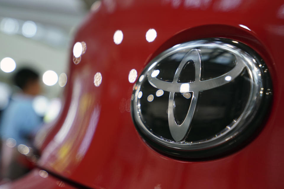 FILE - In this Aug. 2, 2019 file photo, people walk by the logo of Toyota at a show room in Tokyo. Toyota is adding 1.5 million U.S. vehicles to recalls from early 2020 to fix fuel pumps that can fail and cause engines to stall. The company says, Wednesday, Oct. 28, 2020, the latest recall brings the total to 3.3 million Toyota and Lexus brand vehicles that need to be repaired. (AP Photo/Eugene Hoshiko, File)