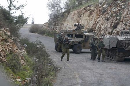 Israeli soldiers walk near military vehicles near Israel's border with Lebanon January 28, 2015. REUTERS/Baz Ratner