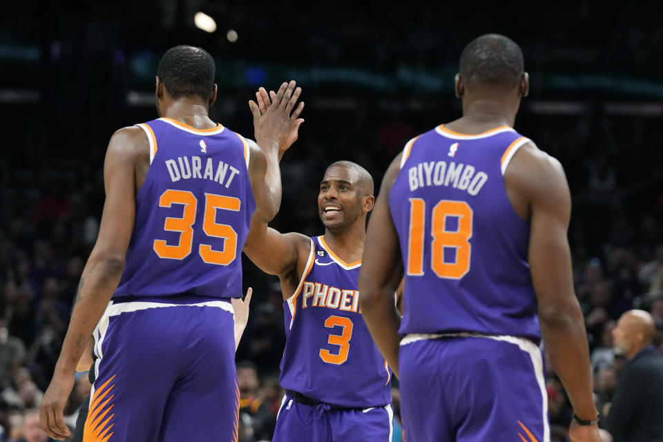 Phoenix Suns guard Chris Paul (3) gives Suns forward Kevin Durant (35) a high-five as Suns center Bismack Biyombo (18) looks on during the second half of an NBA basketball game against the Minnesota Timberwolves Wednesday, March 29, 2023, in Phoenix. The Suns won 107-100. (AP Photo/Ross D. Franklin)