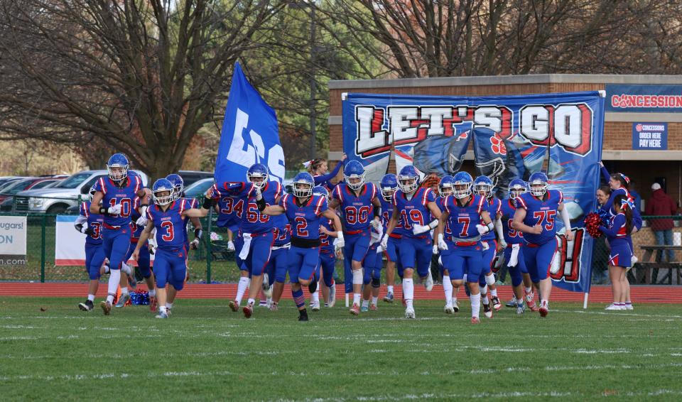 The Lenawee Christian football team runs onto the field for Saturday's Division 2 8-Player semifinal game against Deckerville.