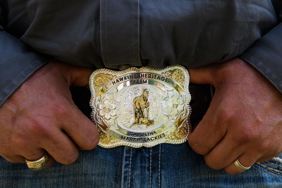 Shannon Hawkins shows off his Hawkins Heritage Farm belt buckle, featuring a Marsh Tacky horse, as he poses for a portrait on April 15, 2021.