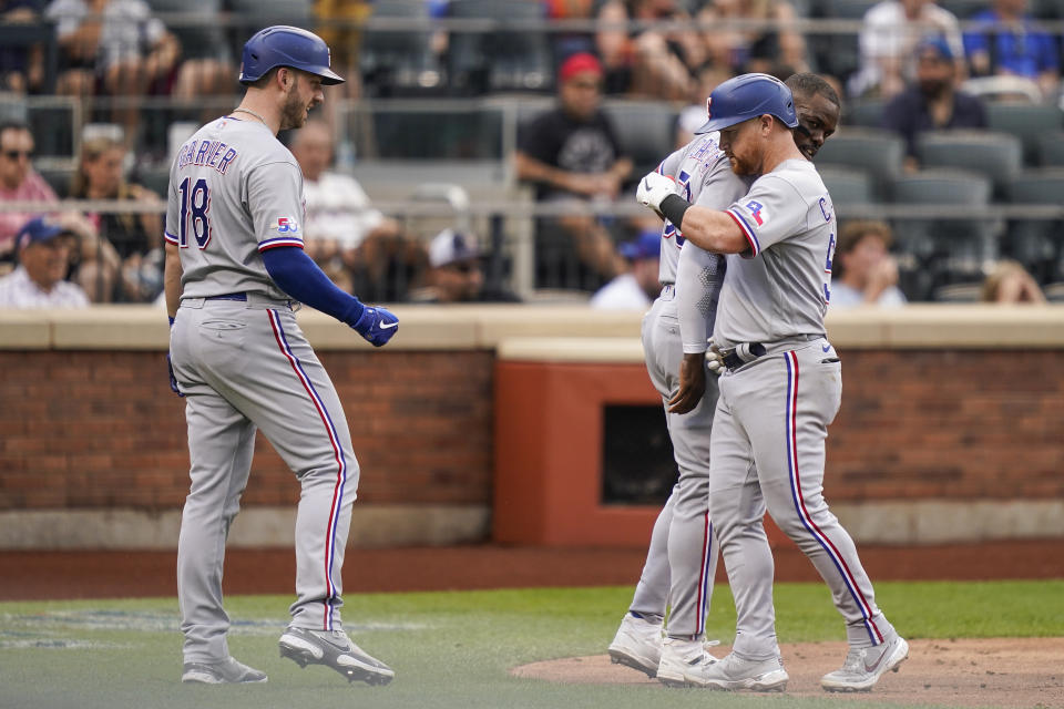 Texas Rangers' Kole Calhoun, right, celebrates with Texas Rangers' Adolis Garcia, center, and Mitch Garver (18) after scoring a three run home run off New York Mets starting pitcher Trevor Williams in the second inning of a baseball game, Saturday, July 2, 2022, in New York. (AP Photo/John Minchillo)