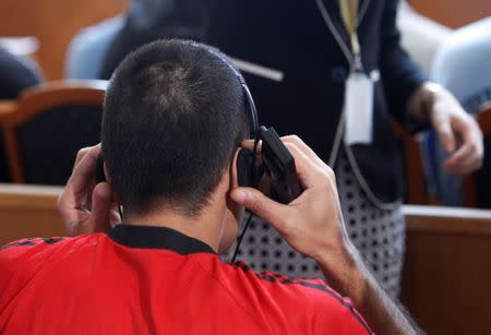 A defendant adjusts his headphones, during the trial in which four men are charged with causing the death of 71 migrants who suffocated in a lorry found beside an Austrian motorway in 2015, in Kecskemet, Hungary June 21, 2017. REUTERS/Bernadett Szabo