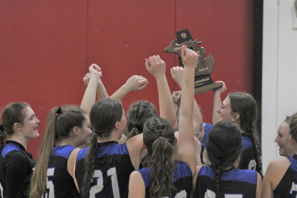 The Inland Lakes girls basketball team celebrates with the trophy after beating Onaway in a MHSAA Division 4 district final at Onaway on Friday.