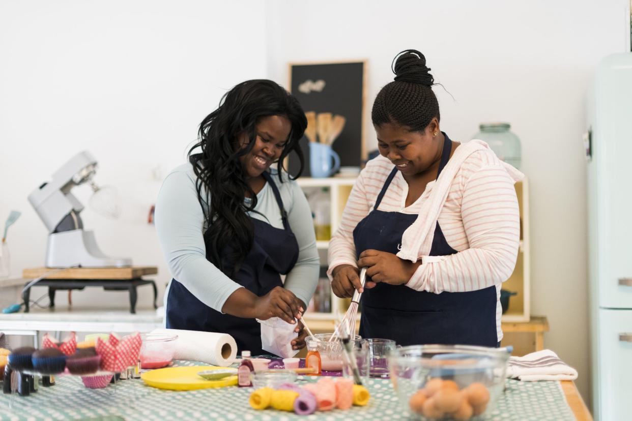 Front view of two woman baking mixing flour in their kitchen