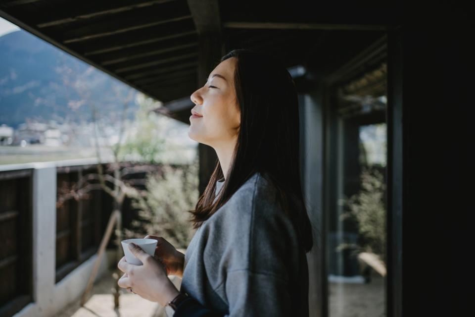 woman drinking coffee and breathing fresh air on balcony in the morning