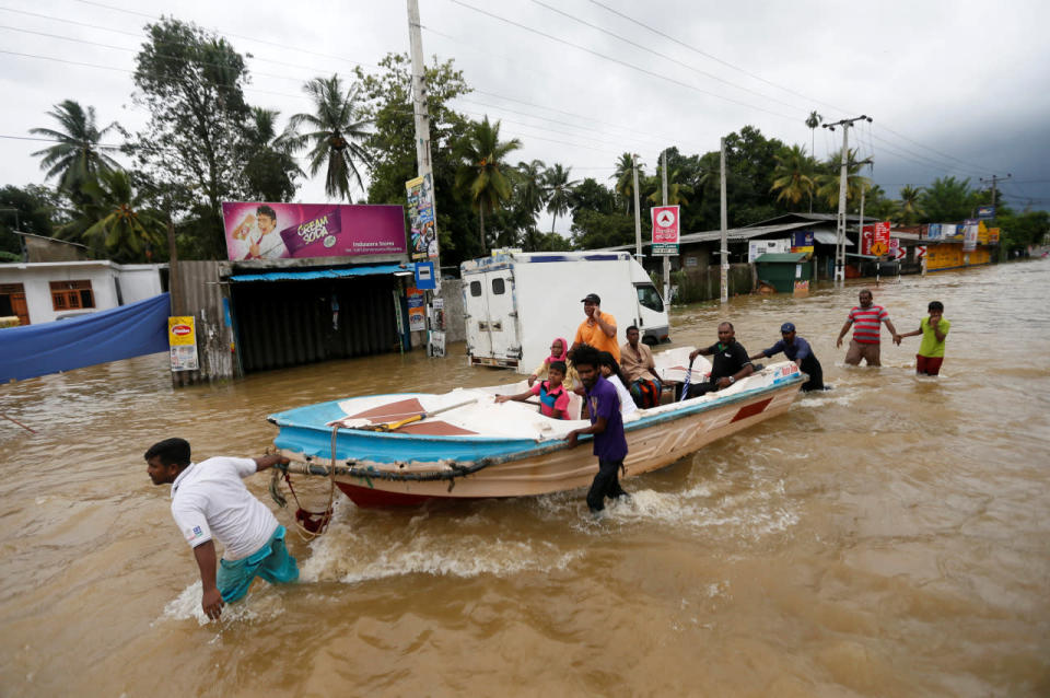 Villagers pull a boat with people rescued from a flooded road in Biyagama, Sri Lanka, May 17, 2016. (Reuters/Dinuka Liyanawatte)