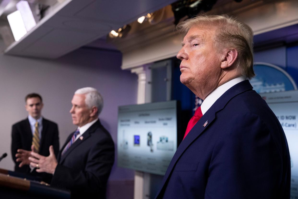 Donald Trump looks on as Mike Pence speaks during a White House briefing on the coronavirus pandemic: AP