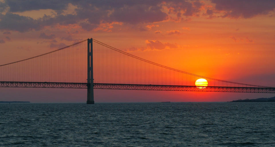 FILE - The sun sets over the Mackinac Bridge, the dividing line between Lake Michigan and Lake Huron, at Michigan's Mackinac Straits on May 31, 2002. Studies predict the Great Lakes and other large freshwater bodies around the world will move toward acidity as they absorb excess carbon dioxide from the atmosphere, which also causes climate change. Experts say acidification could disrupt aquatic food chains and habitat. (AP Photo/Al Goldis, File)