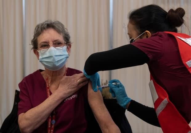 Personal support worker Johanne Lamesse receives the Pfizer-BioNTech COVID-19 vaccine at The Ottawa Hospital on Dec. 15, 2020. The booking system is now up and running for Ottawa's public vaccine clinics, which open later this week. (Adrian Wyld/Canadian Press - image credit)