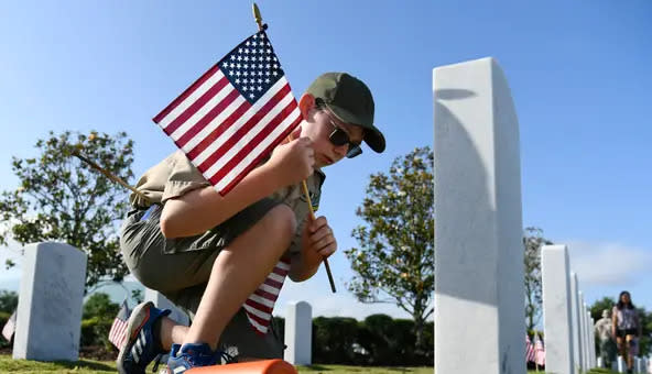 Chase Wilson, 13, of Bradenton, with Boy Scout Troop 10, places an American flag at a grave at Sarasota National Cemetery. He was one of 700 volunteers who took part in May.