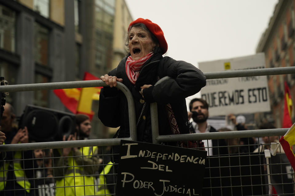 A woman climbs on a barrier to protest against the investiture of Spain's acting Prime Minister Pedro Sanchez after he was chosen by a majority of legislators to form a new government in the Spanish Parliament in Madrid Spain, Thursday, Nov. 16, 2023. Demonstrators are protesting Spain's Socialist's deal which granted amnesty to Catalan separatists in exchange for support of new government. Sign reads 'Independence for the judiciary'. (AP Photo/Andrea Comas)