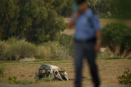 A policeman is seen near a field after a powerful bomb blew up a car (Rear) killing investigative journalist Daphne Caruana Galizia in Bidnija in Bidnija, Malta, October 16, 2017. REUTERS/Darrin Zammit Lupi