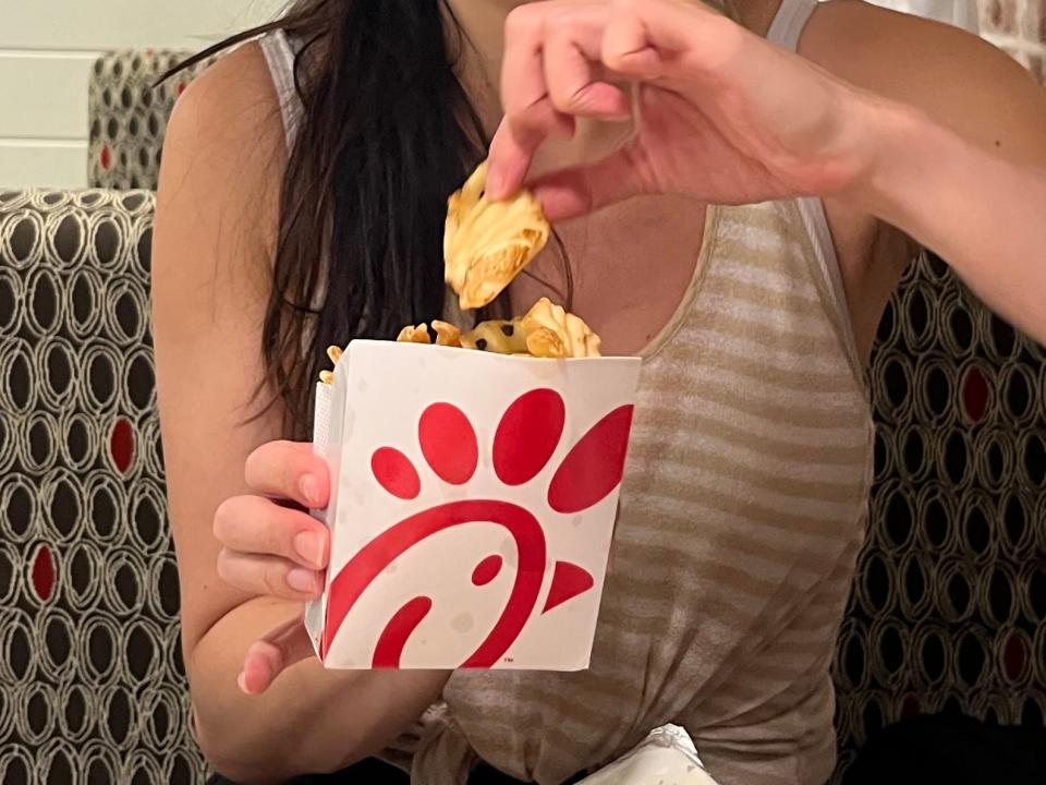 tiffany pulling a waffle fry out of the container at chick fil a