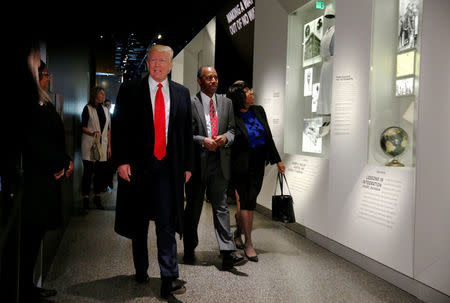 U.S. President Donald Trump and Ben Carson (C), his nominee to lead the Department of Housing and Urban Development (HUD), joined by Carson's wife, Candy Carson, look at the exhibit dedicated to Carson's distinguished career as a neurosurgeon during a visit to the National Museum of African American History and Culture on the National Mall in Washington, U.S., February 21, 2017. REUTERS/Jonathan Ernst