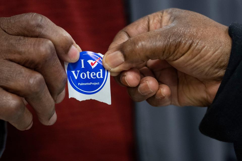 Henry Dirton Jr., 75, receives a sticker after voting at Greenville Senior High School during the Democratic primary election in Greenville, S.C., on Saturday, Feb. 3, 2024.