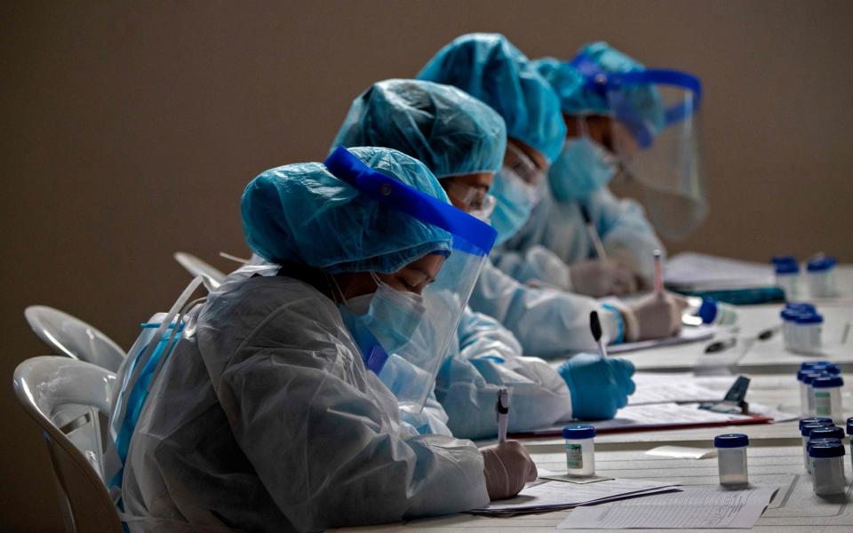 Health workers who conduct Covid-19 tests, do paper work in Bogota amid pandemic - JUAN BARRETO /AFP 