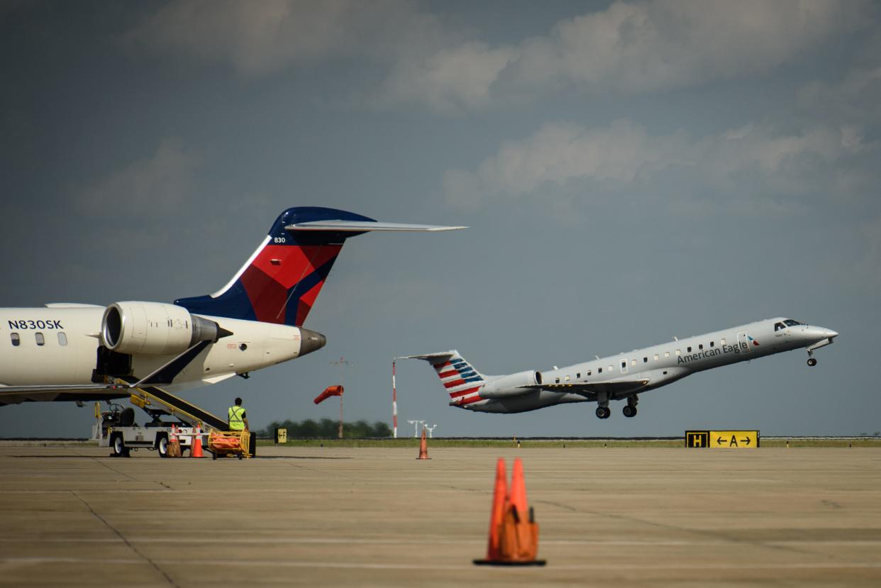 An American Airlines flight takes off as luggage is unloaded from a Delta Airlines jet at Fayetteville Regional Airport on Tuesday, May 7, 2024.