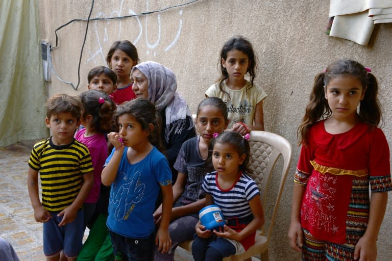 Sana Ibrahim (C-L, behind), a 61-year-old Iraqi matriarch and caretaker for 22 grandchildren, sits with her family in a courtyard in their home in the northern city of Mosul