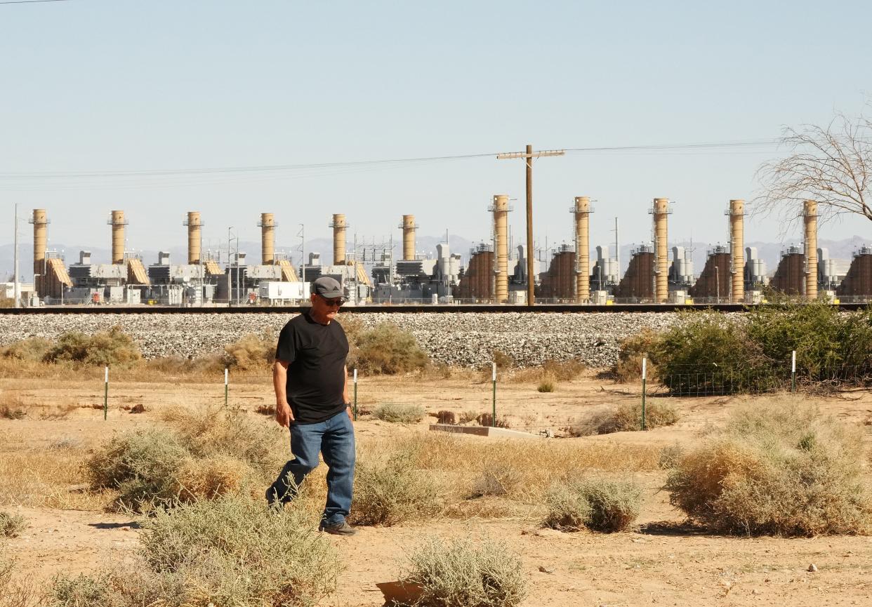 Ron Jordan walks his property with the Salt River Project generating station across the railroad tracks. SRP wants to double the size of its natural gas generating station immediately east of Randolph and his home.