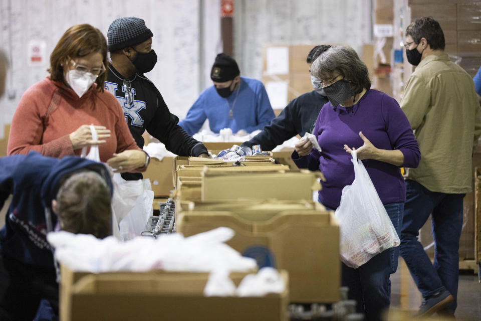 Volunteer Allison Willis, right, fills a bag with food items with other volunteers for the backpack program at Feeding America food bank in Elizabethtown, Ky., Monday, Jan. 17, 2022. Food banks across the country are experiencing a critical shortage of volunteers as the omicron variant frightens people away from group activities. (AP Photo/Michael Clubb)