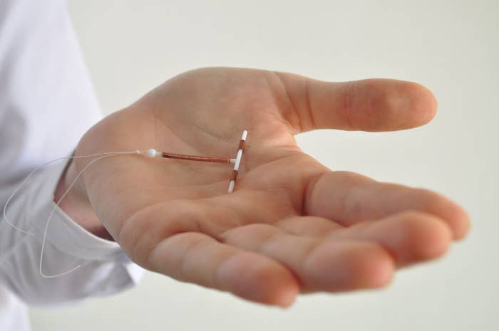 A close-up of someone's hand holding an IUD