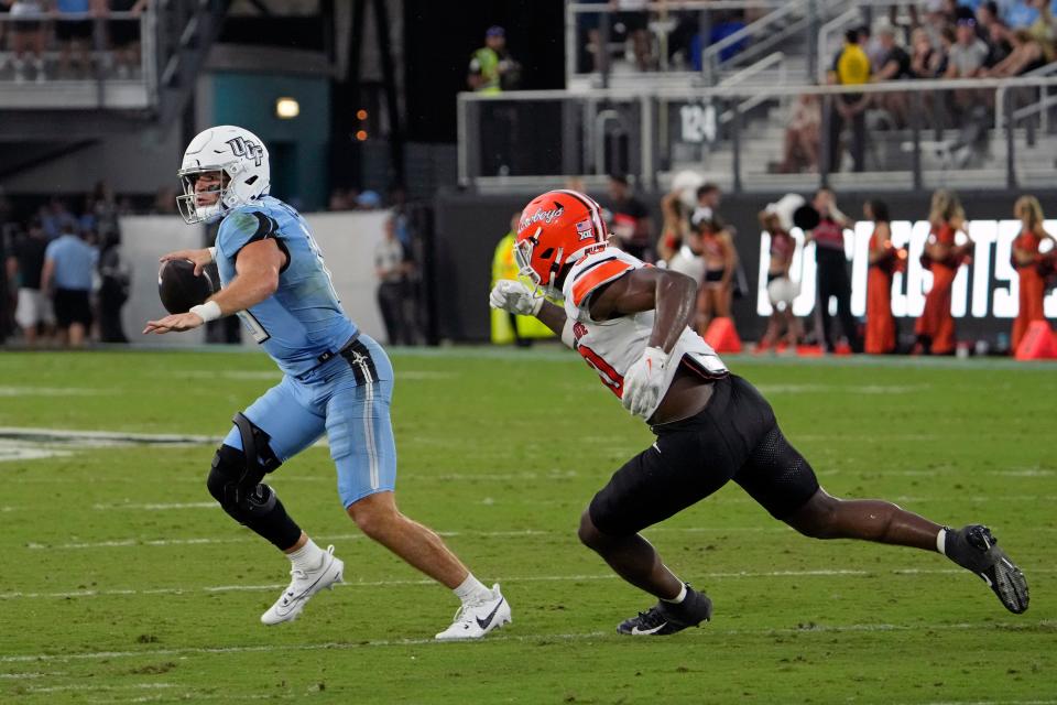 Central Florida quarterback John Rhys Plumlee, left, scrambles from the pocket as Oklahoma State linebacker Collin Oliver gives chase during the first half of an NCAA college football game, Saturday, Nov. 11, 2023, in Orlando, Fla. (AP Photo/John Raoux)