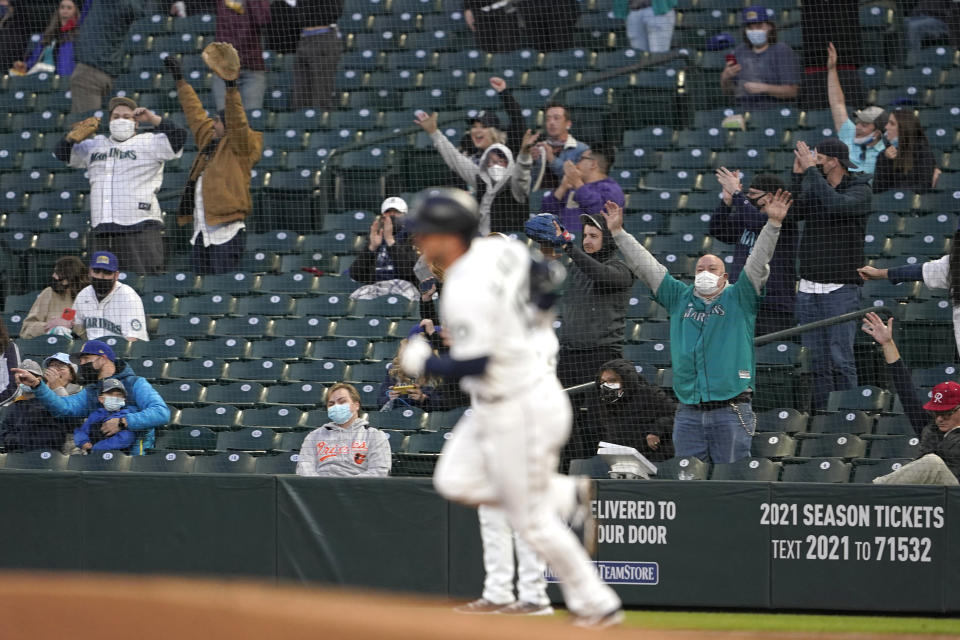 Fans wearing masks as a precaution against COVID-19, cheer as Seattle Mariners' Kyle Seager rounds the bases after hitting a solo home run against the Baltimore Orioles during the fourth inning of a baseball game, Tuesday, May 4, 2021, in Seattle. (AP Photo/Ted S. Warren)