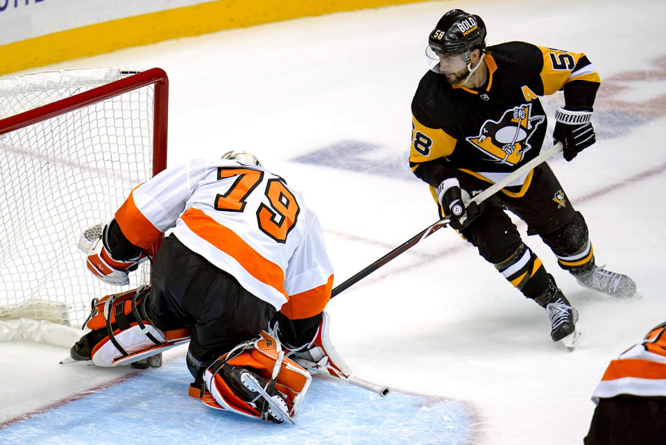 Pittsburgh Penguins' Kris Letang (58) backhands the puck under the pad of Philadelphia Flyers goaltender Carter Hart (79) for an overtime goal in an NHL hockey game in Pittsburgh, Thursday, Nov. 4, 2021. The Penguins won 3-2. (AP Photo/Gene J. Puskar)