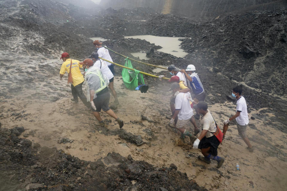 People use poles to carry a recovered body shrouded in green plastic Friday, July 3, 2020 in Hpakant, Kachin State, Myanmar. More than 100 people were killed Thursday in a landslide at a jade mine in northern Myanmar, the worst in a series of deadly accidents at such sites in recent years. (AP Photo/Zaw Moe Htet)