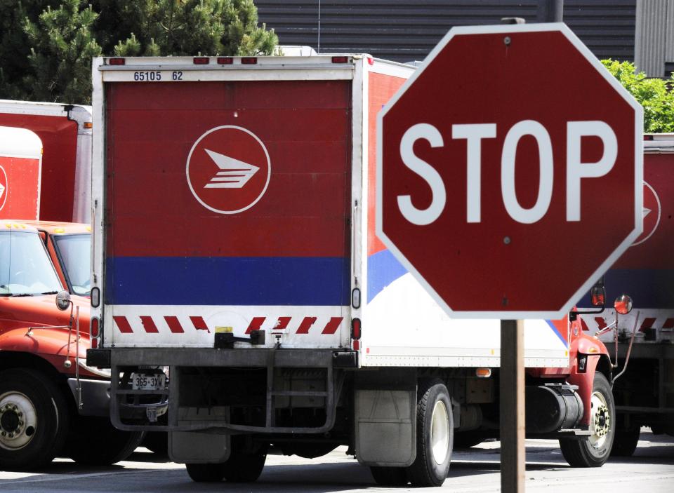 Mail trucks are seen as they are parked behind a stop sign after the Canadian Union of Postal Workers (CUPW) were locked out at a Canada Post sorting facility in Toronto, in this June 15, 2011, file Delivery facility such as a postal box (12 per cent of Canadian) costs Canada Post $59 per address. REUTERS/Mark Blinch/Files