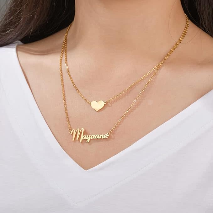 heart charm necklace above gold nameplate necklace