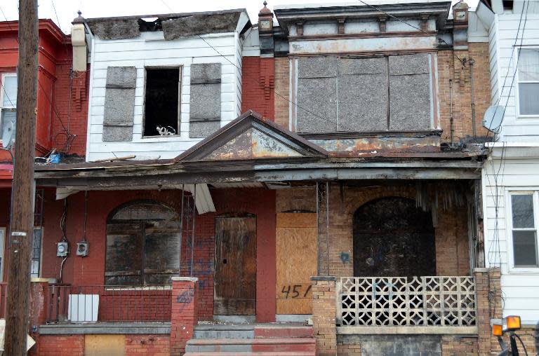 A cat sitting in the window of a boarded up house along a street in Camden, New Jersey, April 4, 2014