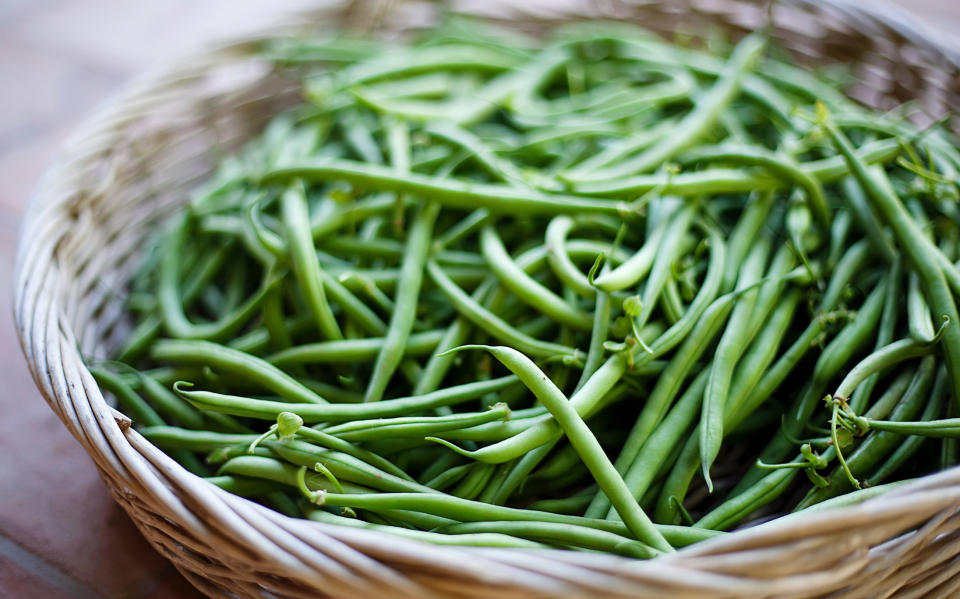 A wide basket filled with fresh green beans