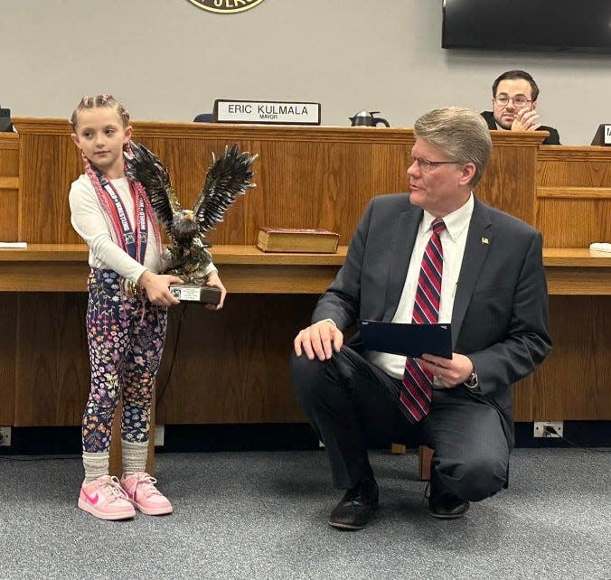 Oakland wrestler Quinn Cannici, 7, displays her Tulsa Nationals trophy as Mayor Eric Kulmala presents her with Certificarte of Recognition at a recent council meeting.