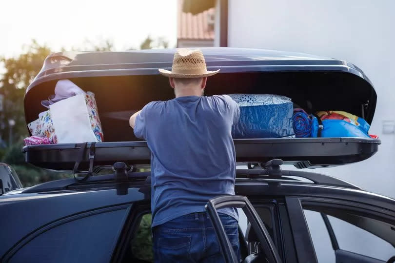 A man packing a box on his roof rack