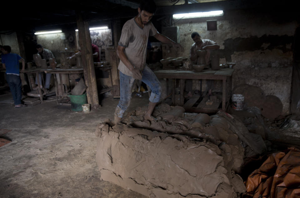 In this Saturday, July 6, 2019 photo, a Palestinian worker prepares the clay at a pottery workshop in Gaza City. Talk about old Gaza, and what pops up are images of clay pottery, colorful glassware, bamboo furniture and ancient frame looms weaving bright rugs and mats. As such professions could be dying worldwide, the pace of their declining is too fast in Gaza that out of its some 500 looms, only one is still functioning. (AP Photo/Khalil Hamra)