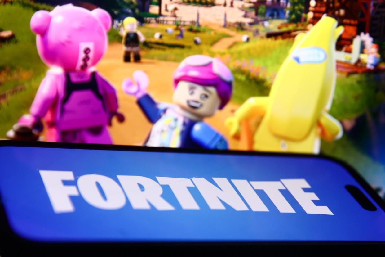The LEGO Fortnite website displayed on a laptop screen and the Fortnite logo displayed on a phone screen.