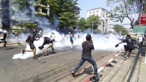 In this image from a video, anti-coup protesters run away from tear gas launched by security forces in Yangon, Myanmar Monday, March 1, 2021. Defiant crowds returned to the streets of Myanmar's biggest city on Monday, determined to continue their protests against the military's seizure of power a month ago, despite security forces having killed at least 18 people around the country just a day earlier. (AP Photo)